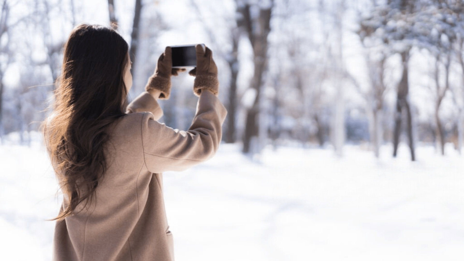 Woman taking a photo on her smartphone of a snowy parking lot